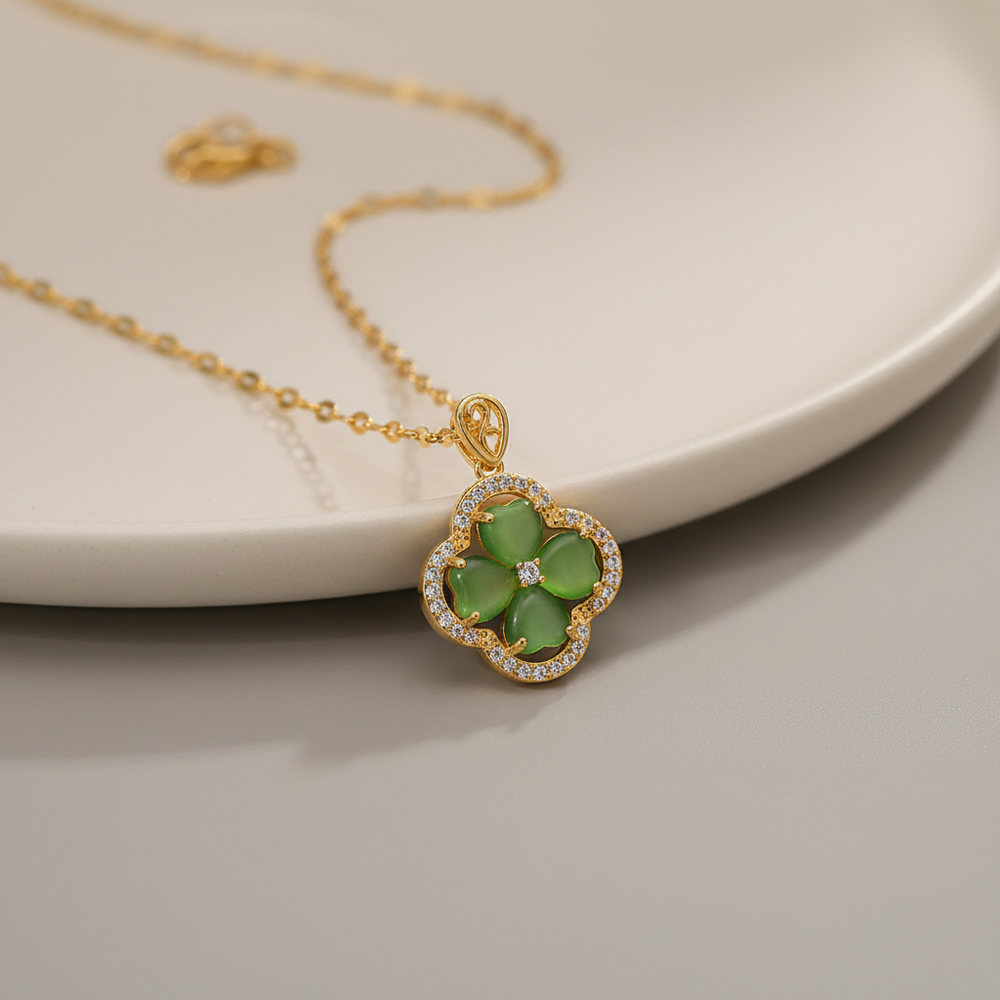 Gold necklace with a green clover pendant on a neutral background
