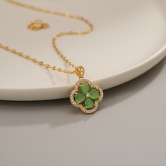 Gold necklace with a green clover pendant on a neutral background