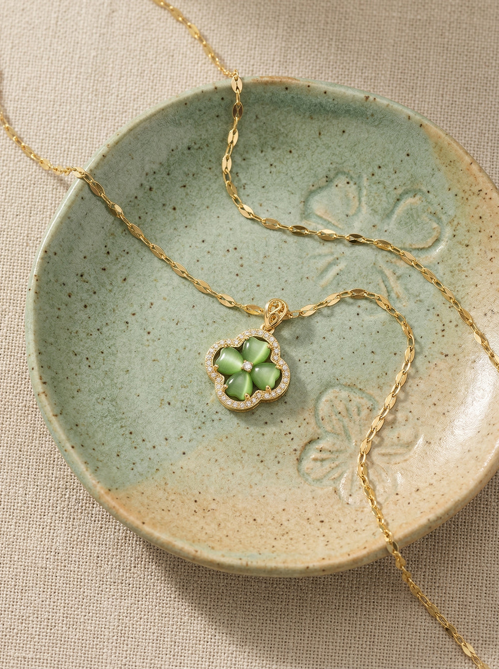Necklace with a clover-shaped pendant on a ceramic dish
