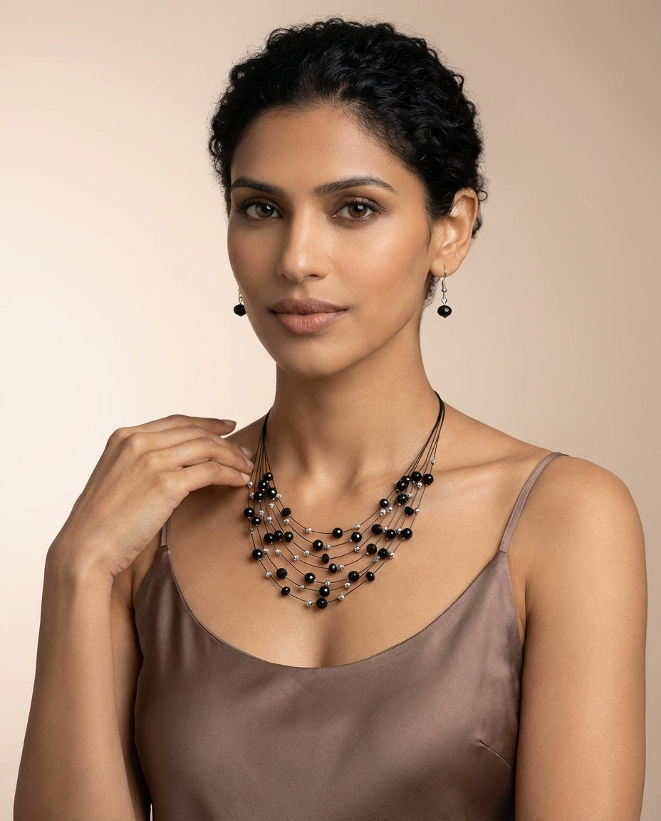 Woman wearing a black beaded necklace and earrings on a beige background
